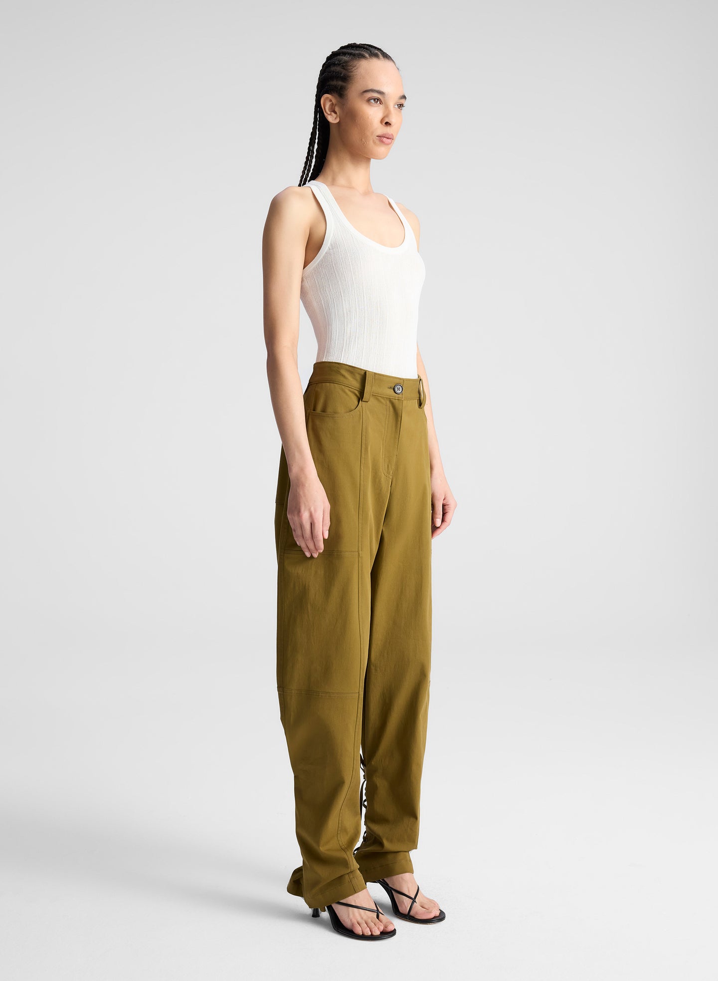 woman wearing white fine gauge voile knit tank top and green pants with tie tapering detail