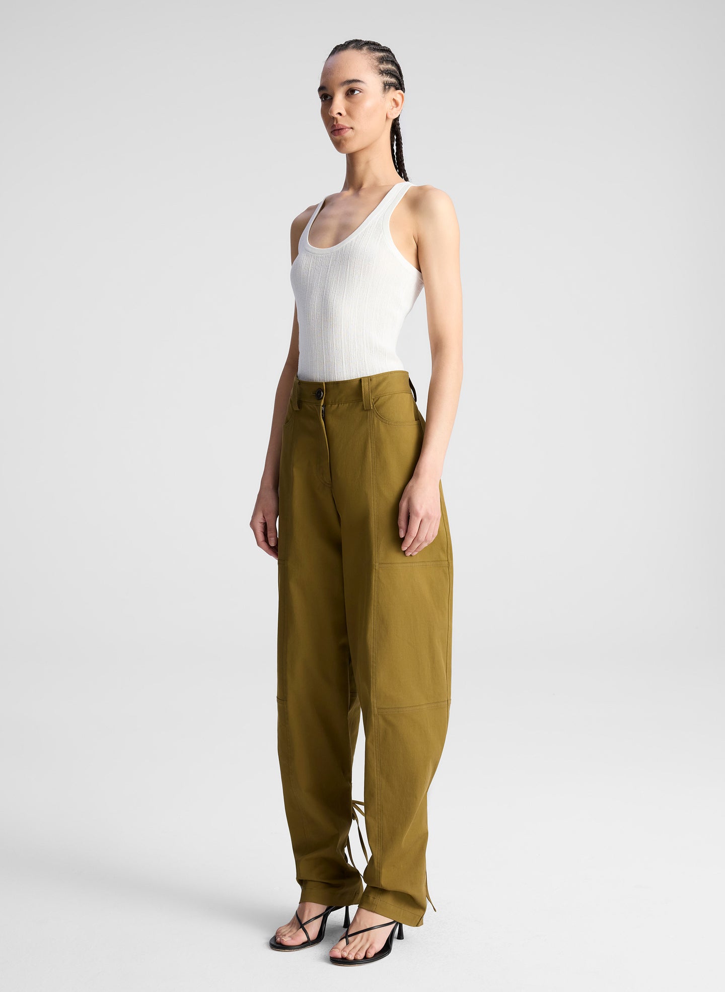woman wearing white fine gauge voile knit tank top and green pants with tie tapering detail