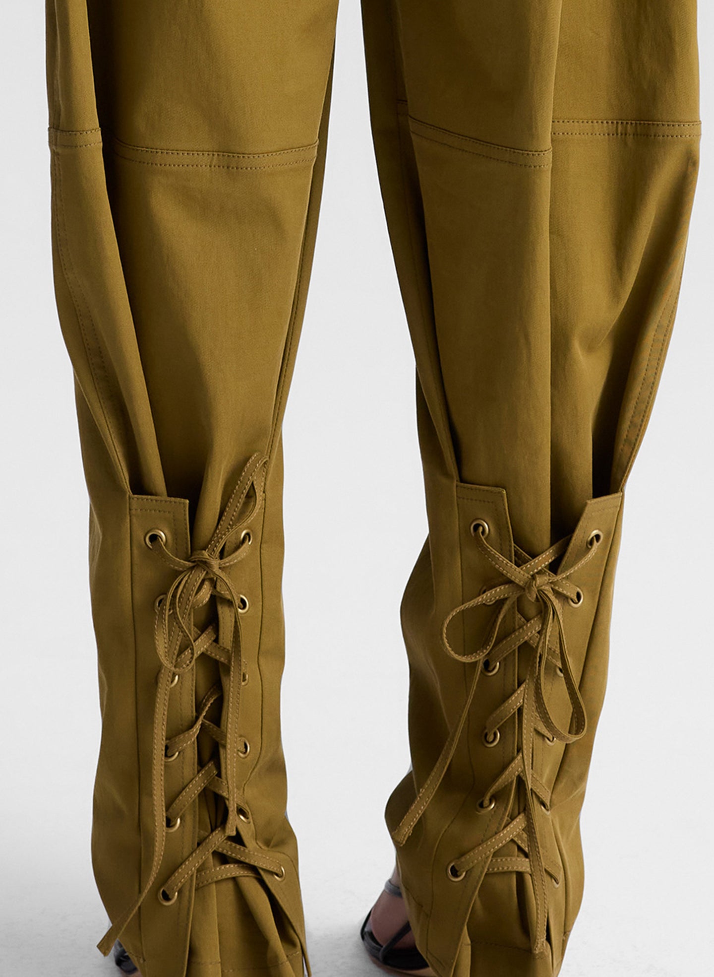 woman wearing white fine gauge voile knit tank top and green pants with tie tapering detail