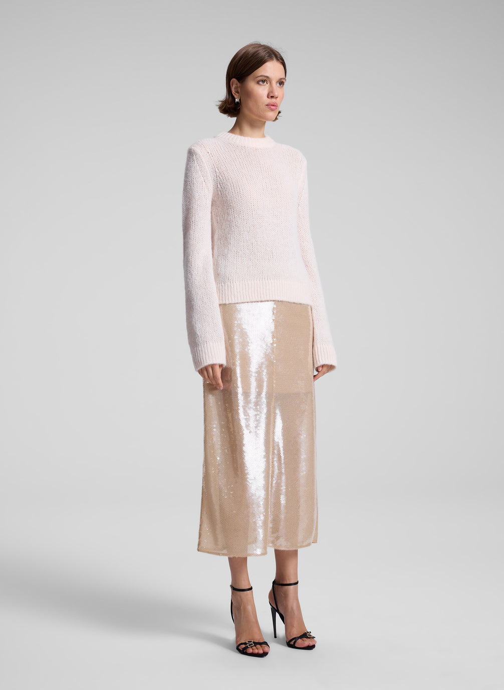 woman wearing light pink sweater and sequin midi skirt