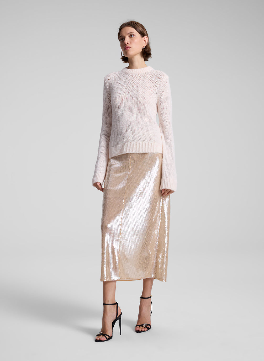 woman wearing light pink sweater and sequin midi skirt