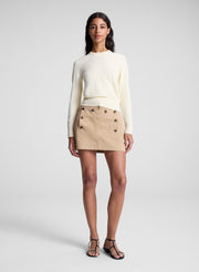 woman wearing butter yellow sweater and tan sailor button mini skirt