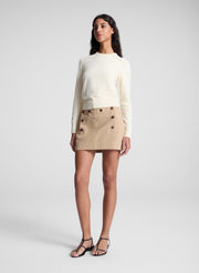 woman wearing butter yellow sweater and tan sailor button mini skirt