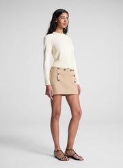 woman wearing butter yellow sweater and tan sailor button mini skirt