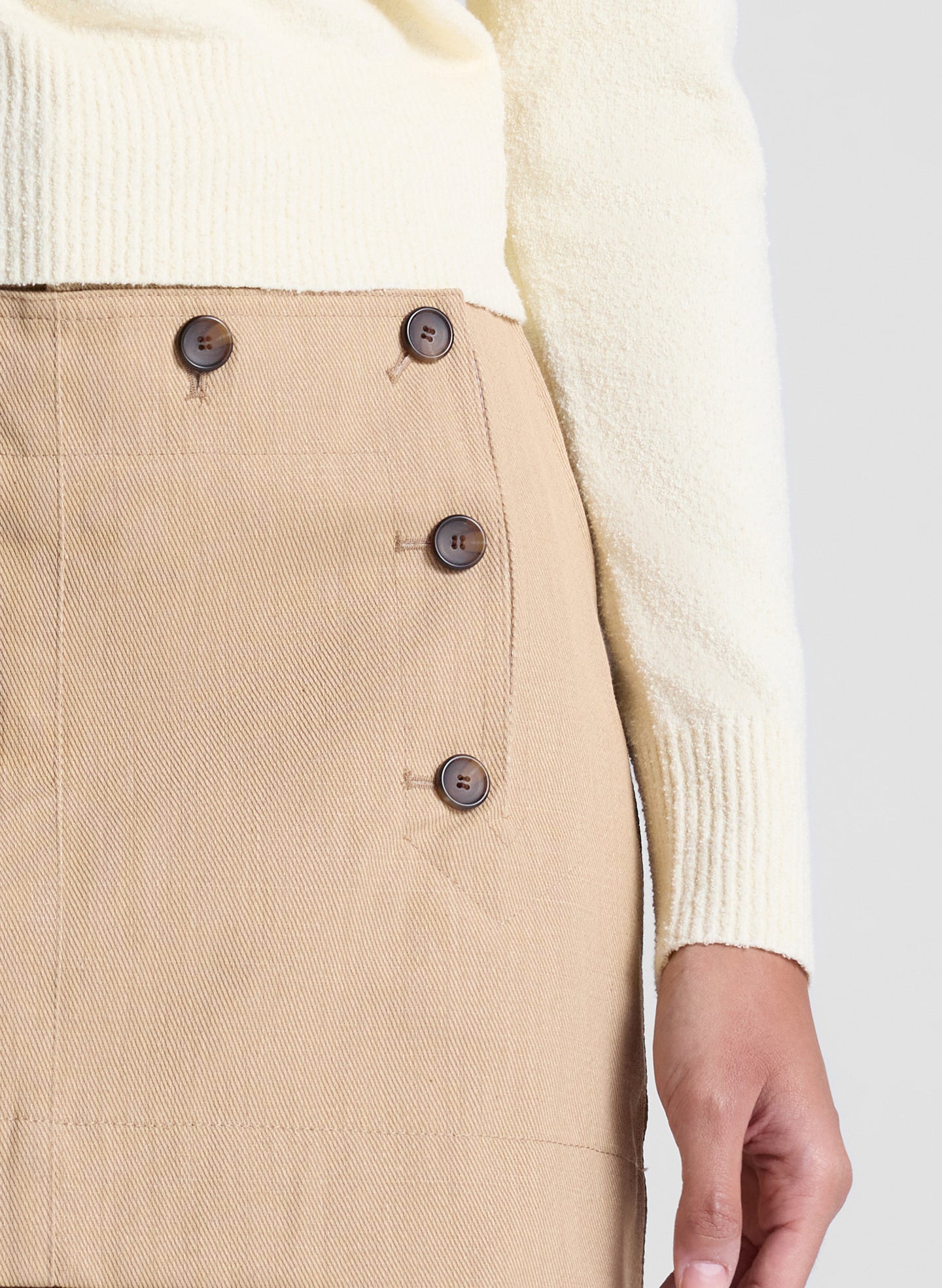 woman wearing butter yellow sweater and tan sailor button mini skirt