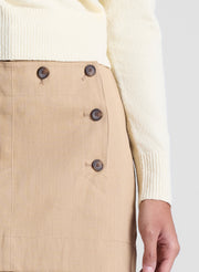 woman wearing butter yellow sweater and tan sailor button mini skirt