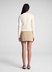 woman wearing butter yellow sweater and tan sailor button mini skirt