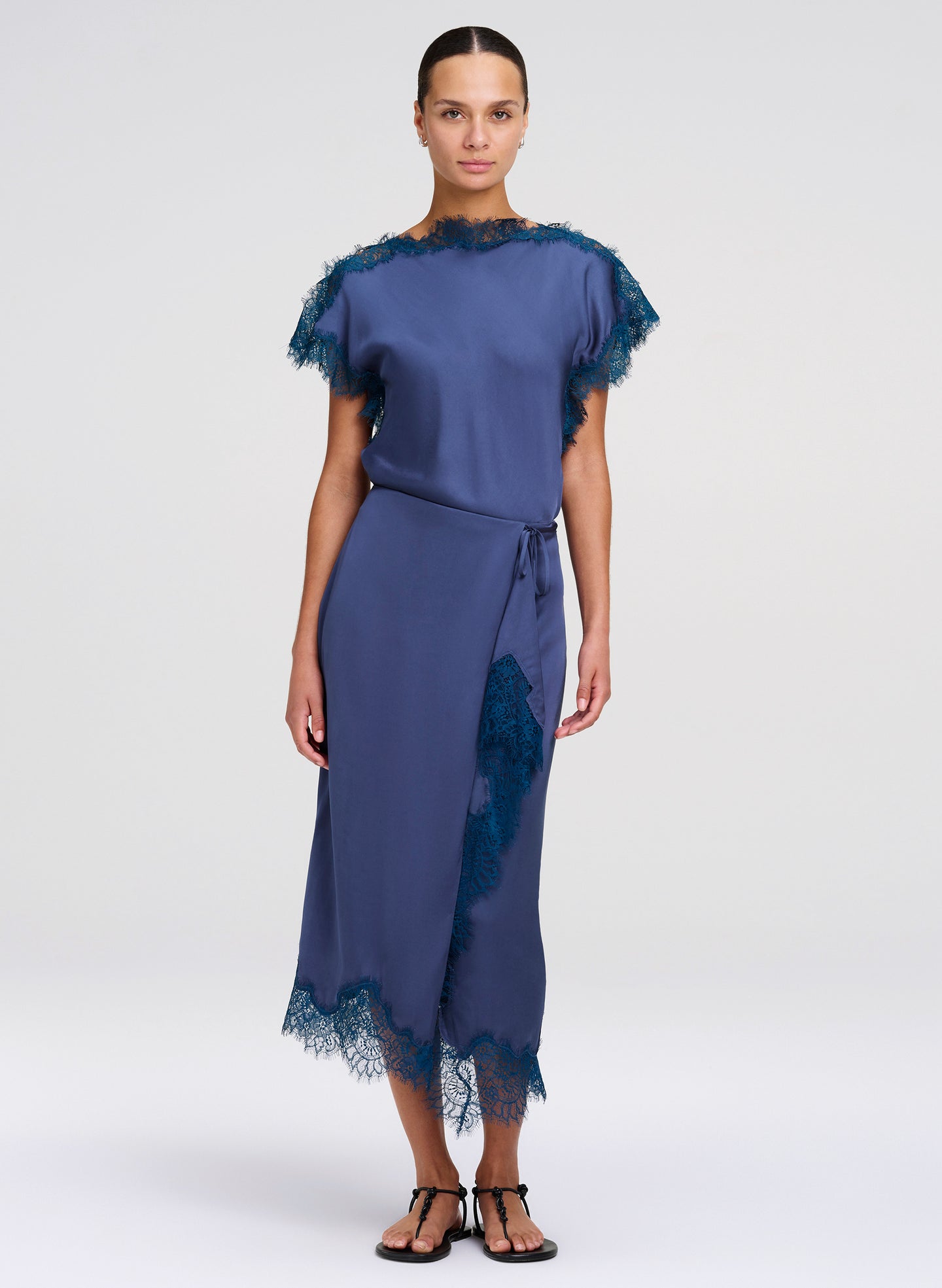 Woman wearing a blue top and skirt with lace details on a white background