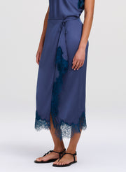 Woman wearing a blue top and skirt with lace details on a white background