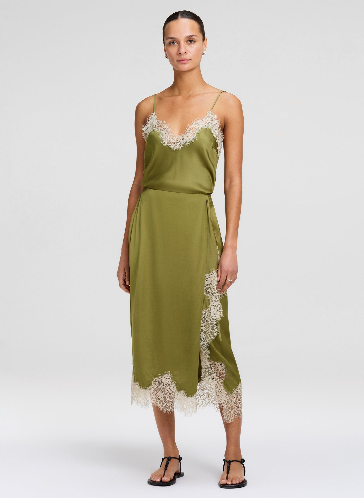 Woman wearing a green camisole and matching skirt with lace trim on a white background
