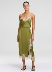 Woman wearing a green camisole and matching skirt with lace trim on a white background