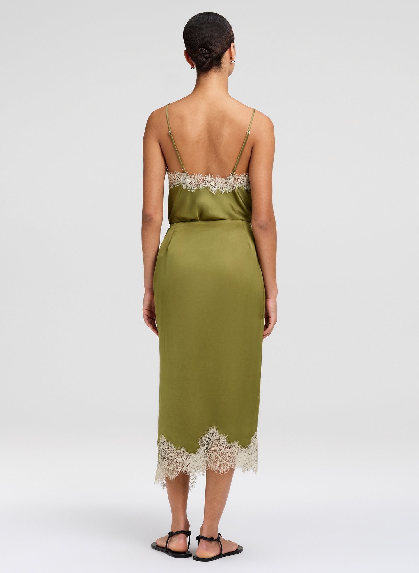 Woman wearing a green outfit with lace details on a white background