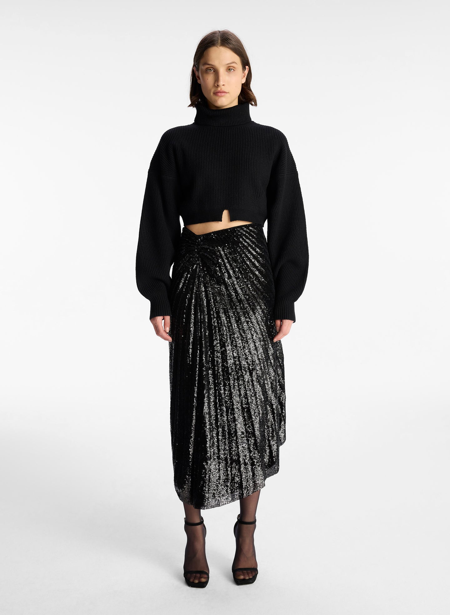 front view of woman wearing black long sleeve turtleneck wool sweater in cropped length with small split in the front hemline 
