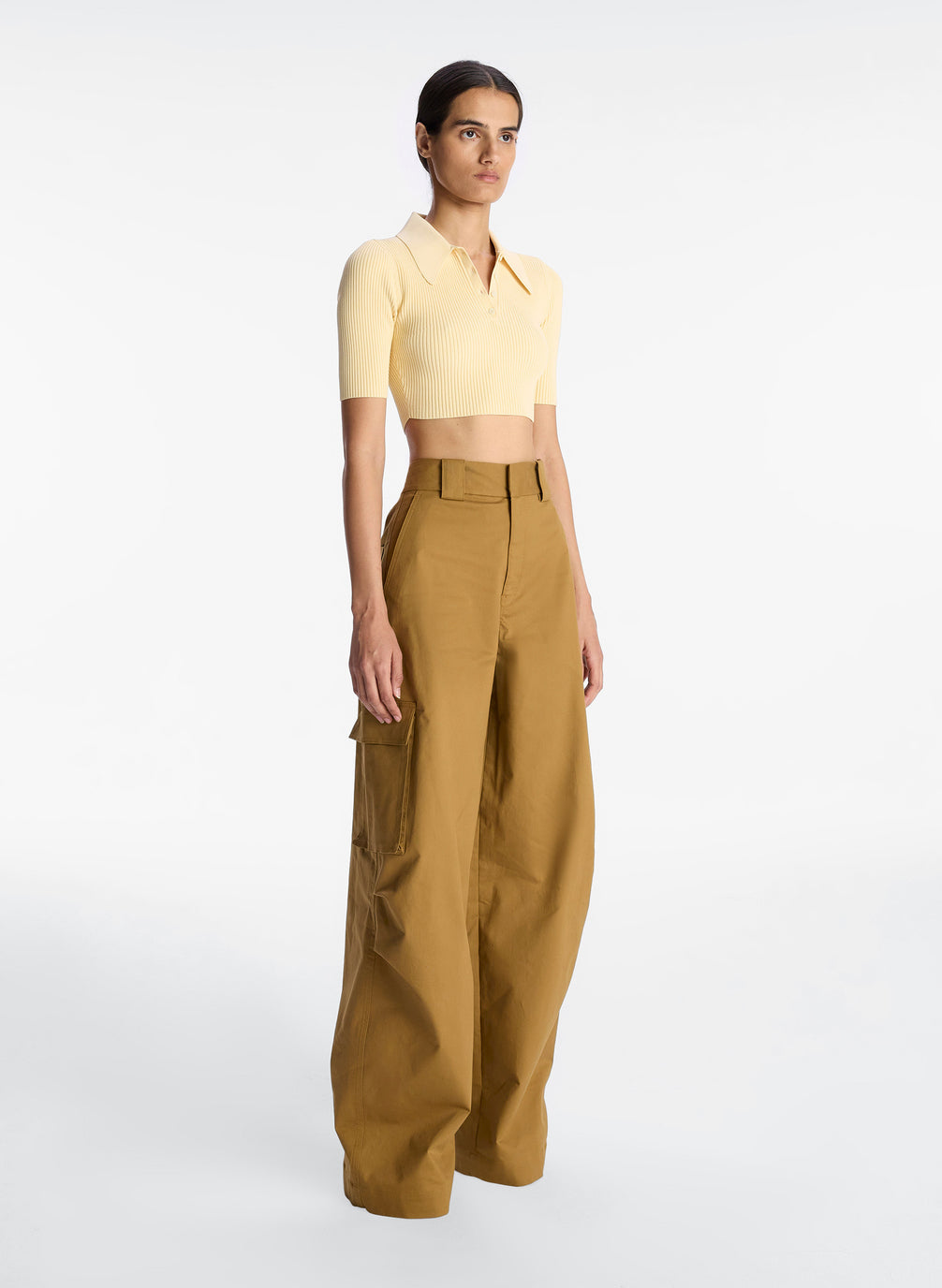 side view of woman wearing yellow cropped collared shirt and tan cargo pants