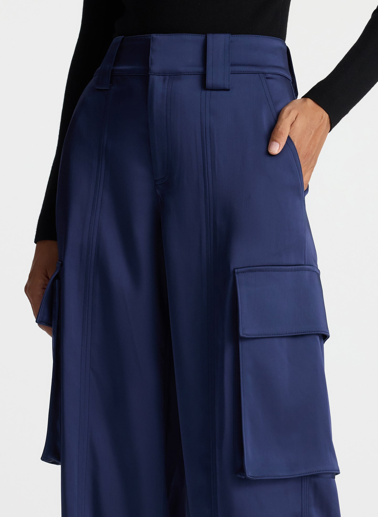 detail view of woman wearing black knit long sleeve top and blue satin cargo pants