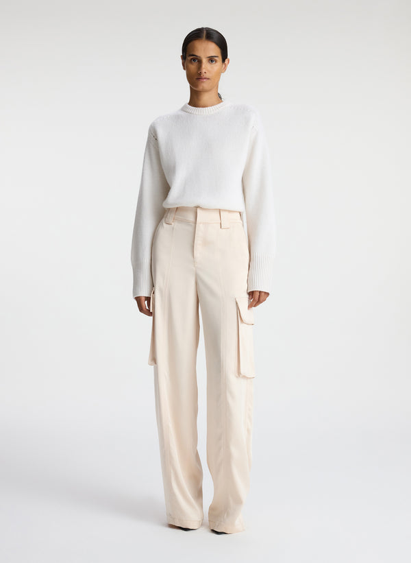 front view of woman wearing white sweater and beige satin cargo pants
