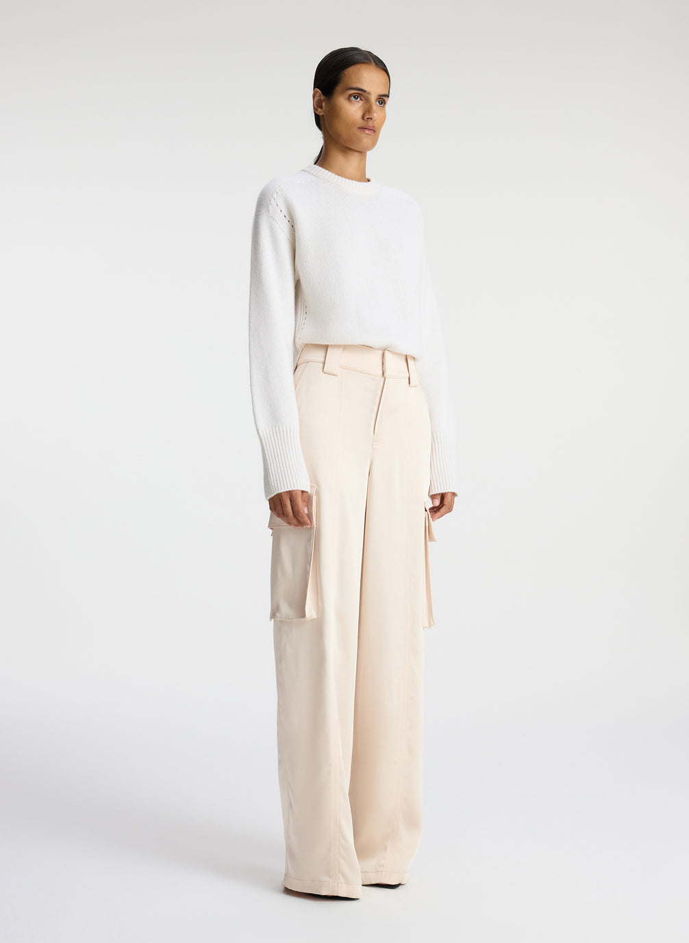 side view of woman wearing white sweater and beige satin cargo pants
