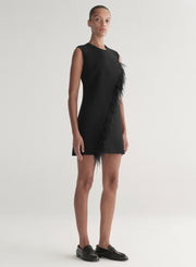 Black sleeveless dress with feather details on a neutral background