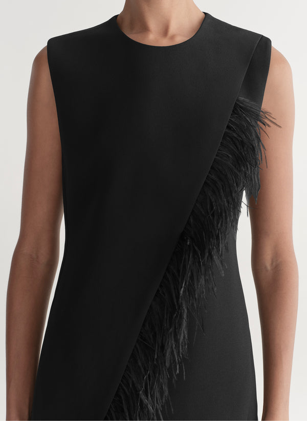 Black sleeveless dress with feather details on a neutral background