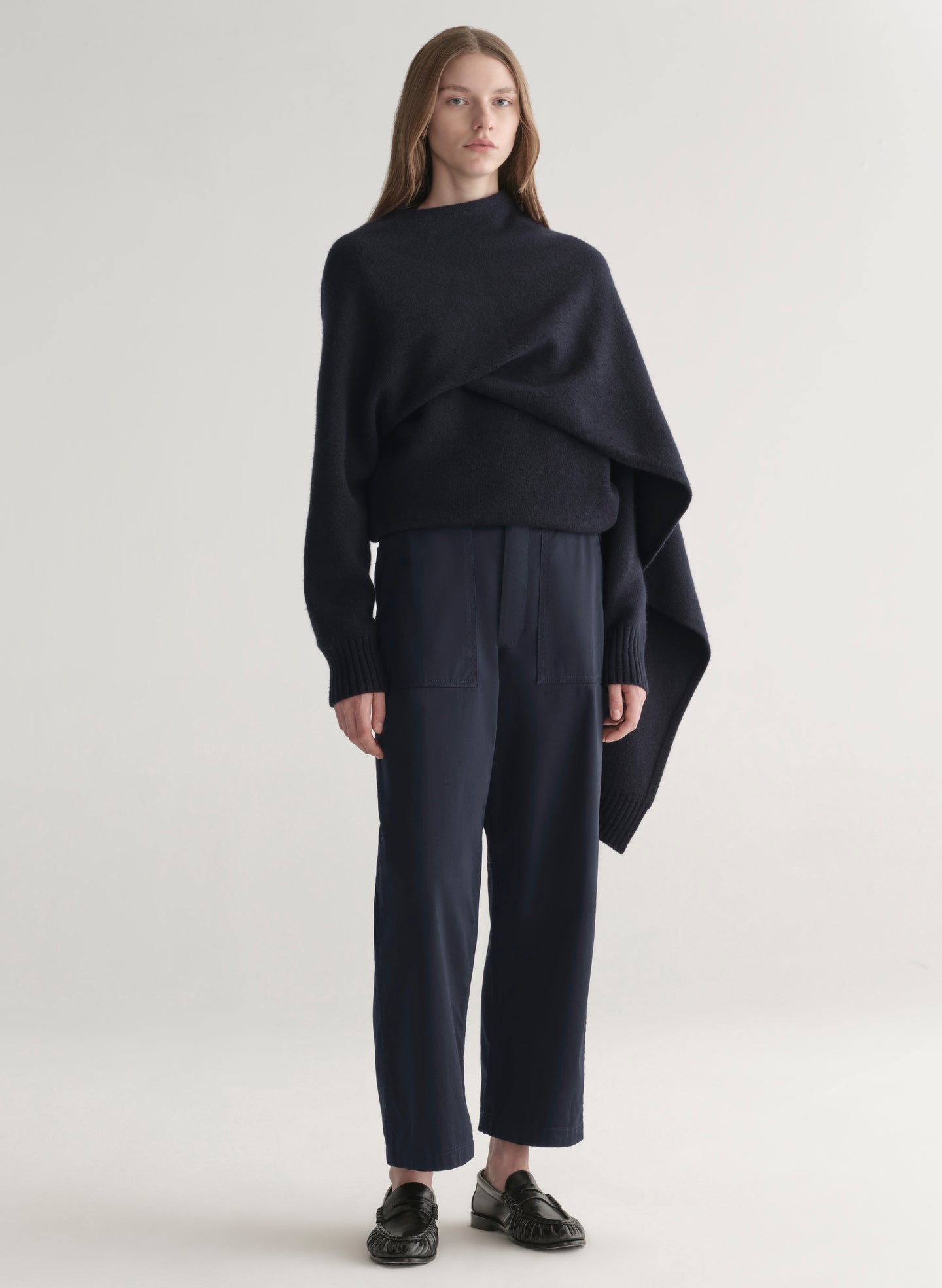 woman wearing a dark blue sweater and pants on a light background