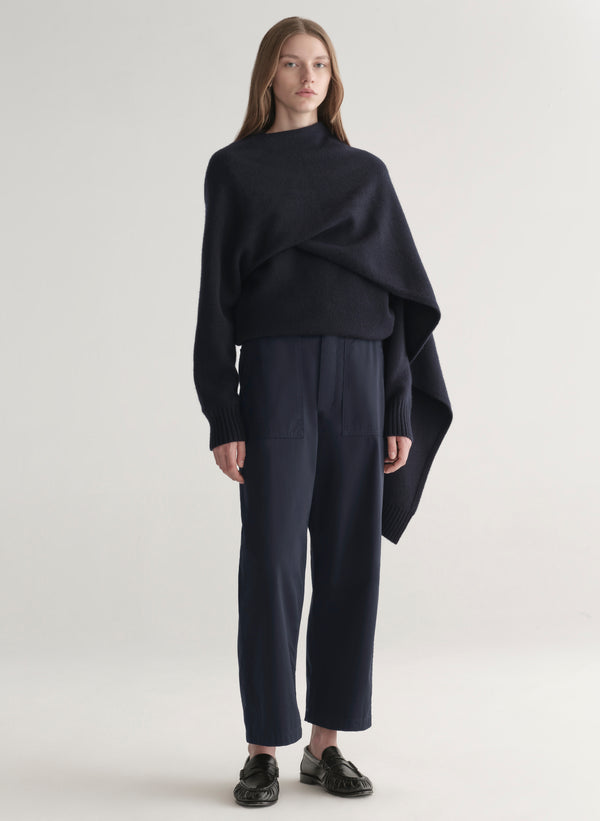 woman wearing a dark blue sweater and pants on a light background