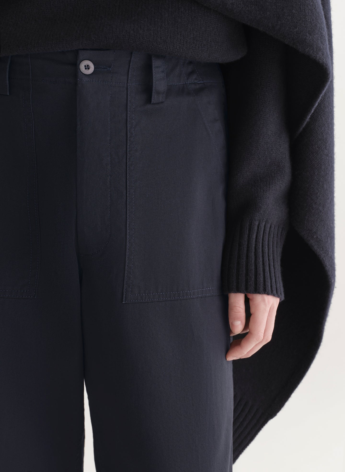 woman wearing a dark blue sweater and pants on a light background