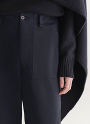 woman wearing a dark blue sweater and pants on a light background