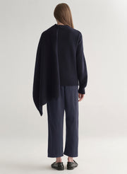 woman wearing a dark blue sweater and pants on a light background