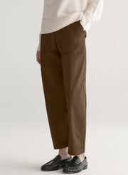 Woman wearing a white sweater and olive green pants on a plain background