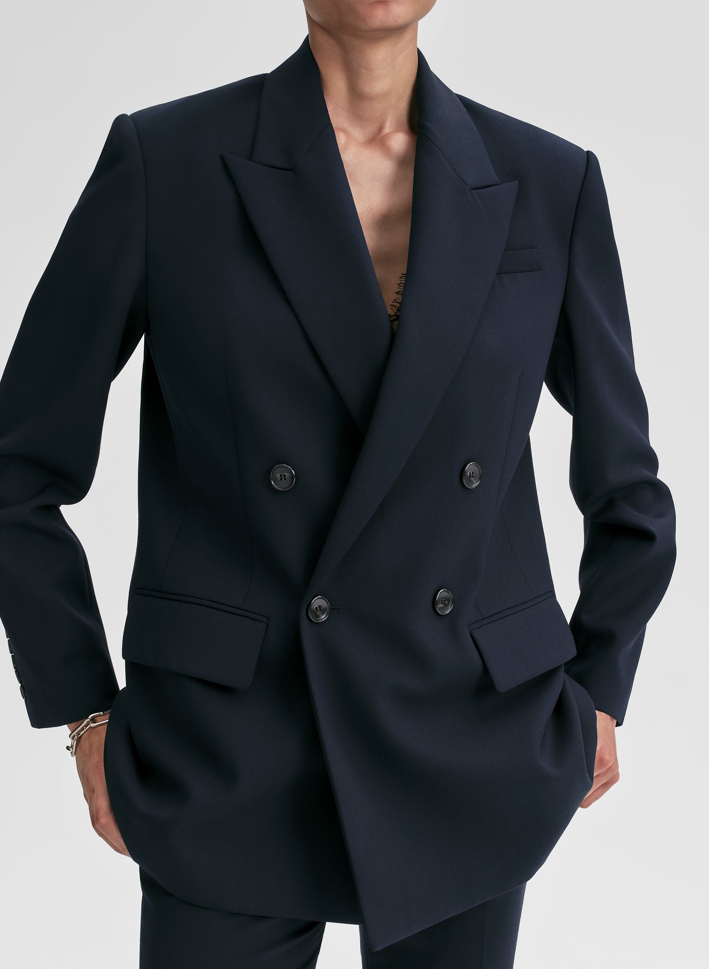 Person wearing a navy blue double-breasted blazer on a light gray background