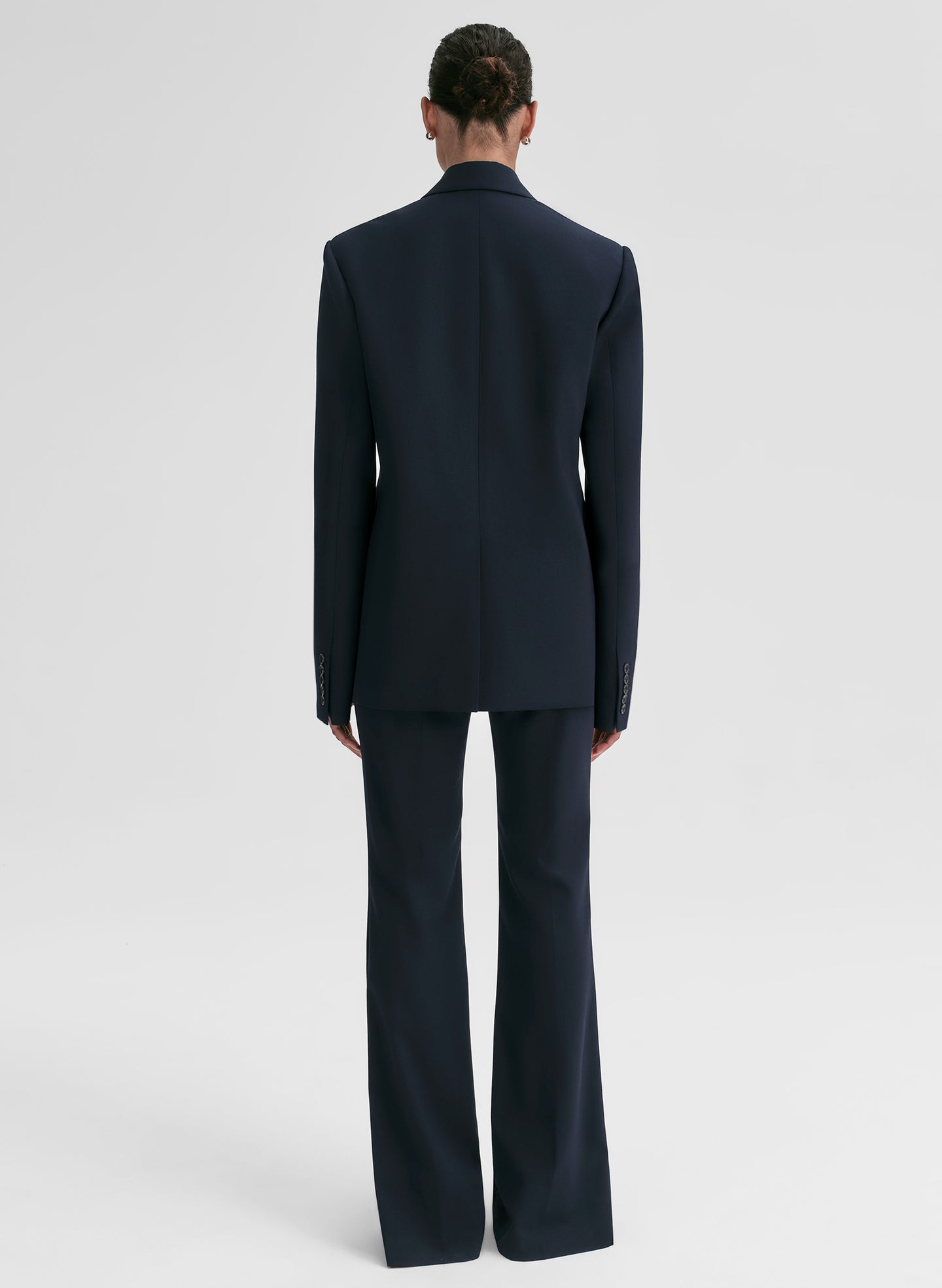 Person wearing a navy blue double-breasted blazer on a light gray background