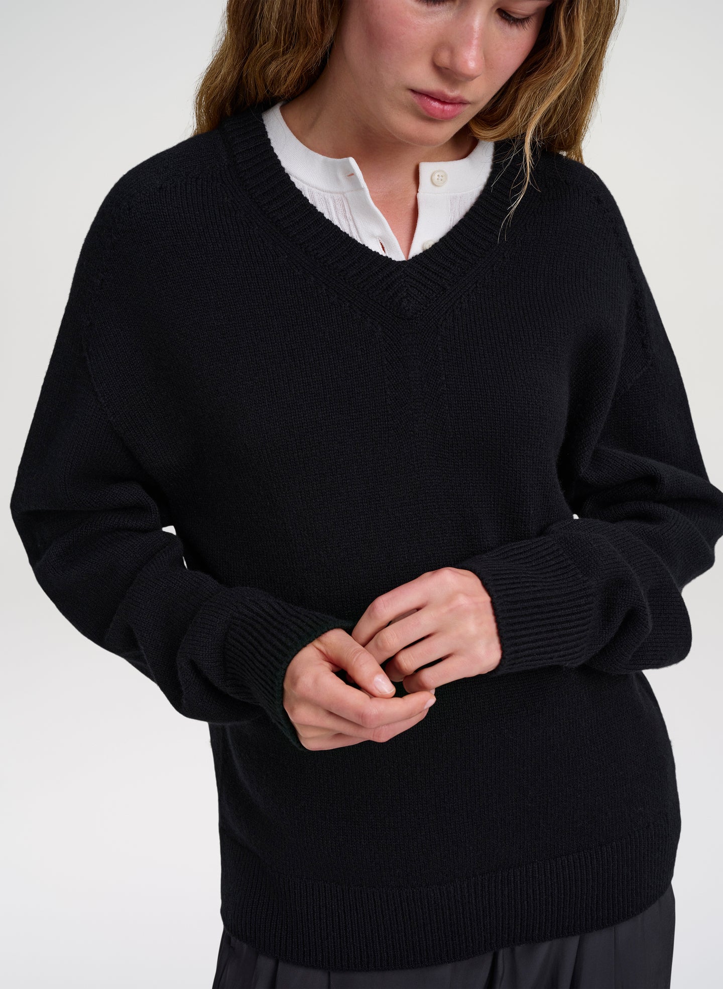 woman wearing black v neck sweater with white shirt underneath