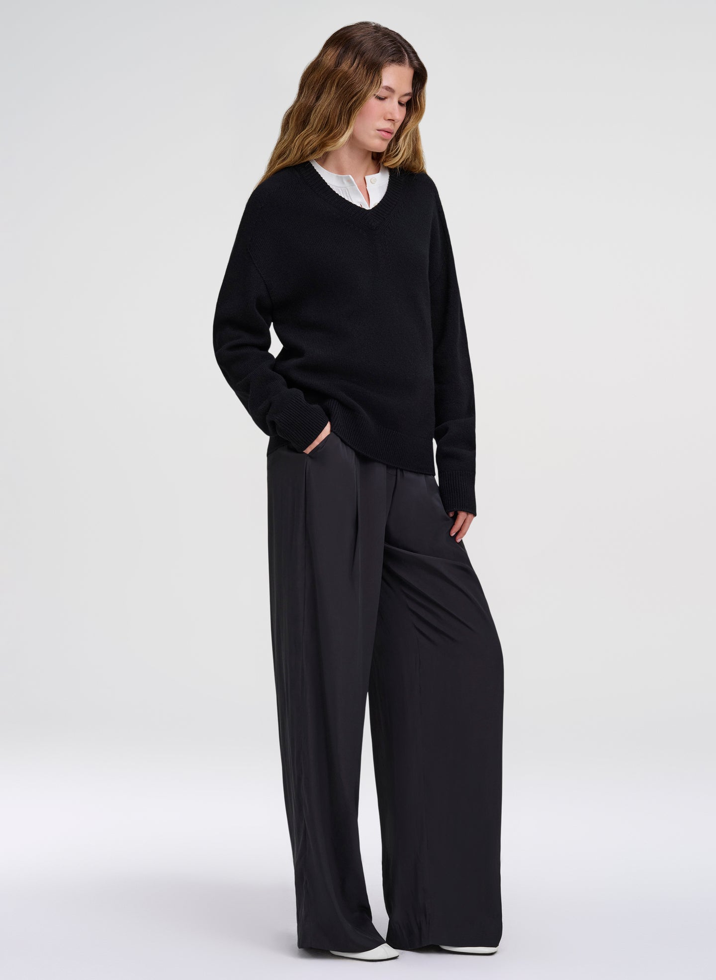 woman wearing black v neck sweater layered with white top and black pants