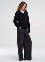 woman wearing black v neck sweater layered with white top and black pants
