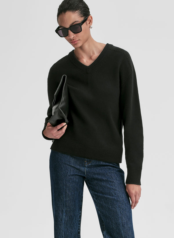 woman wearing black v neck cashmere sweater and blue jeans