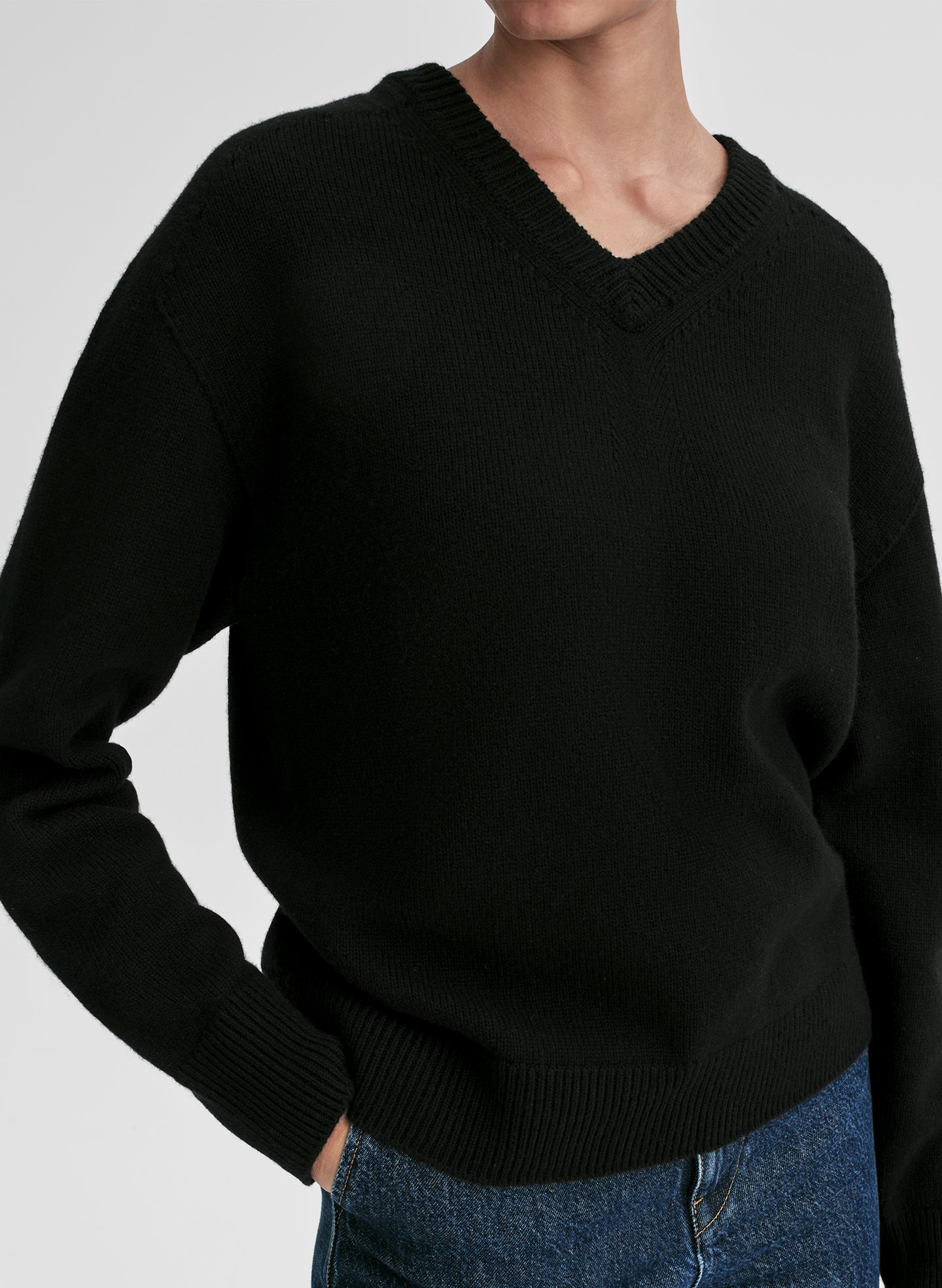 woman wearing black v neck cashmere sweater and blue jeans