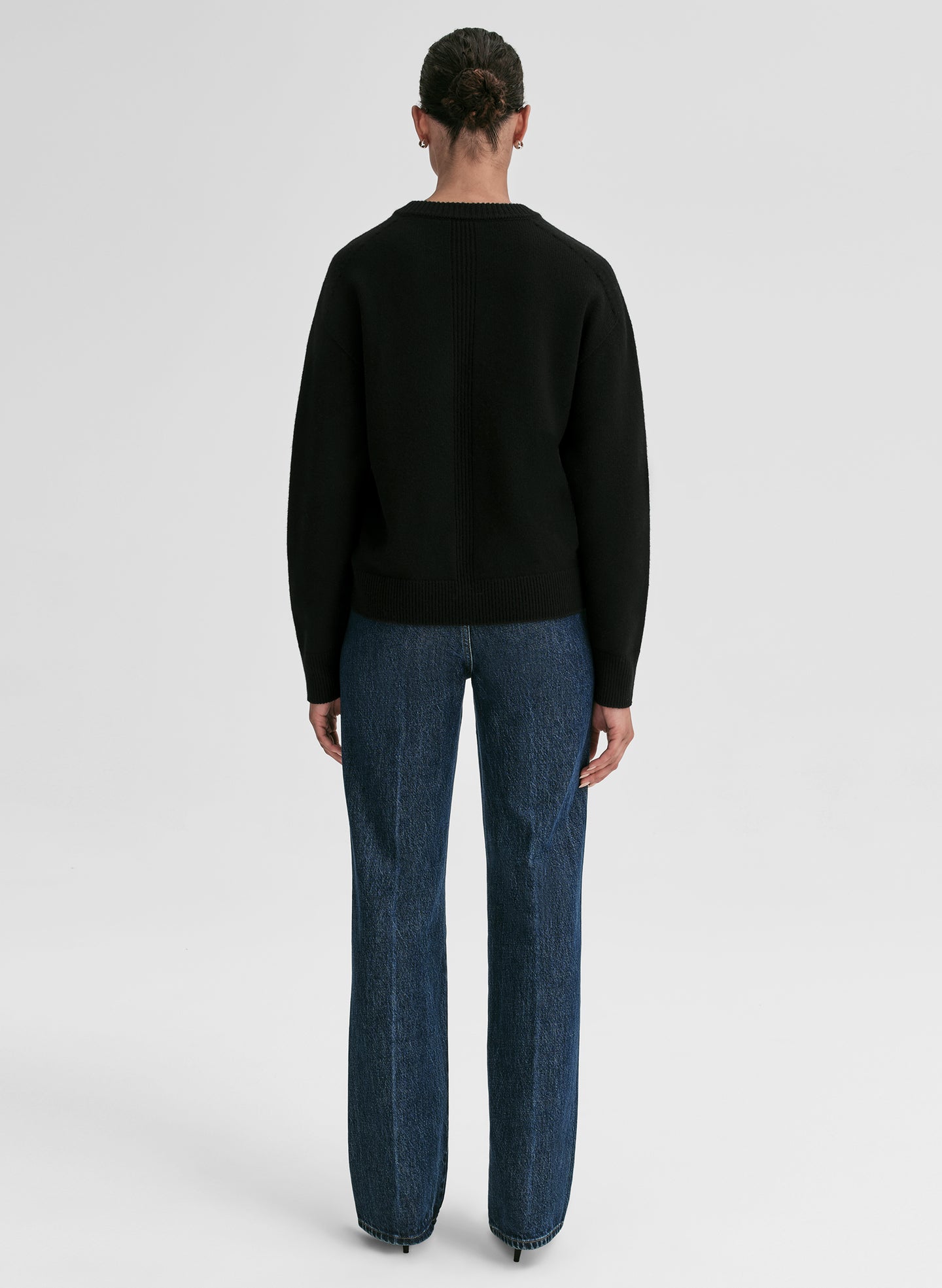 woman wearing black v neck cashmere sweater and blue jeans