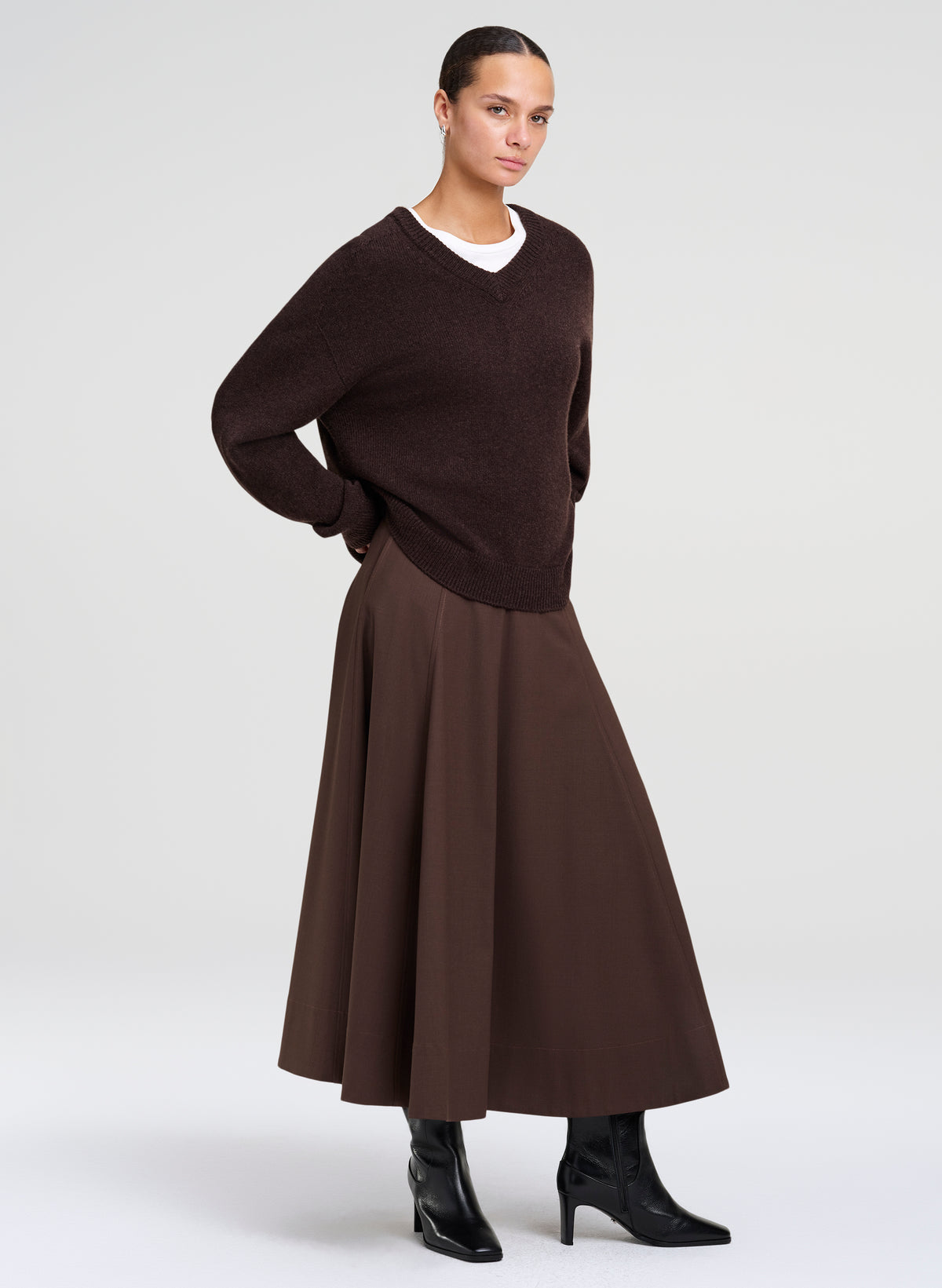 woman wearing brown sweater, white shirt ,  and brown skirt