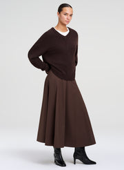 woman wearing brown sweater, white shirt ,  and brown skirt