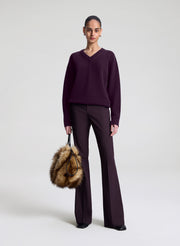 woman wearing vneck sweater and pants with faux fur bag