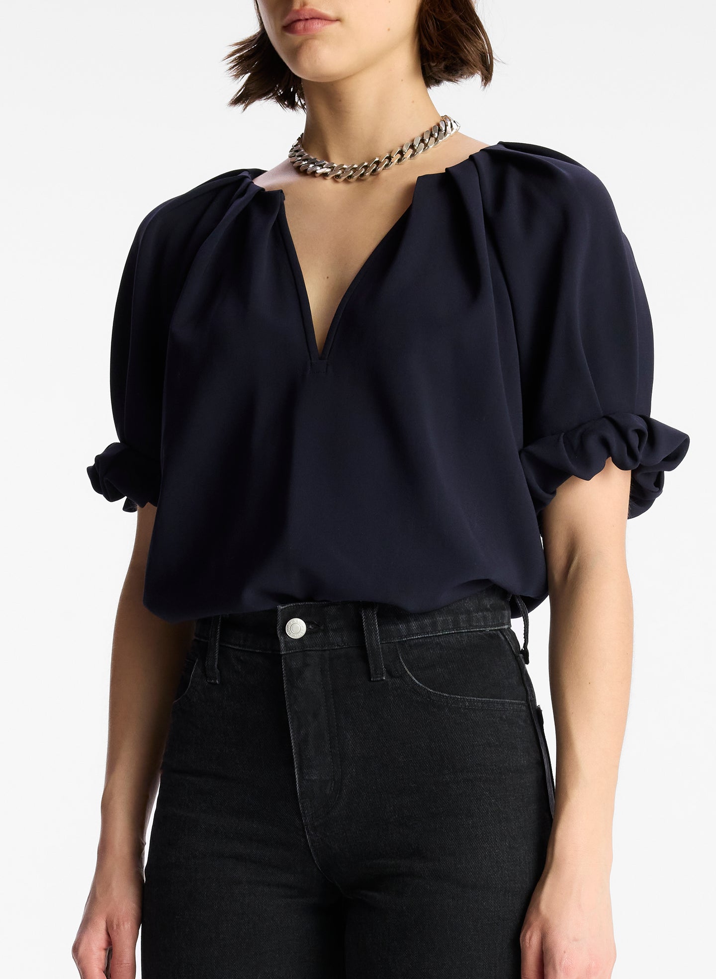 front view of woman wearing navy blue short sleeve vneck top and dark wash denim