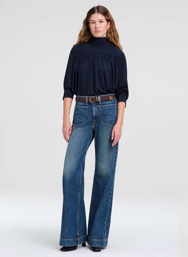 woman wearing blue top, blue denim jeans and a brown suede belt