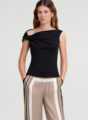 Woman wearing a black one-shoulder top and patterned pants on a white background