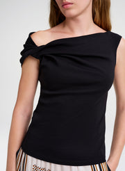 Black one-shoulder top worn by a model on a white background