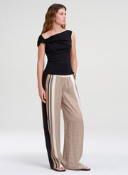 Woman wearing a black off-shoulder top and patterned pants on a white background