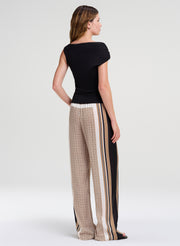 Woman wearing a black top and patterned pants with side stripes on a white background