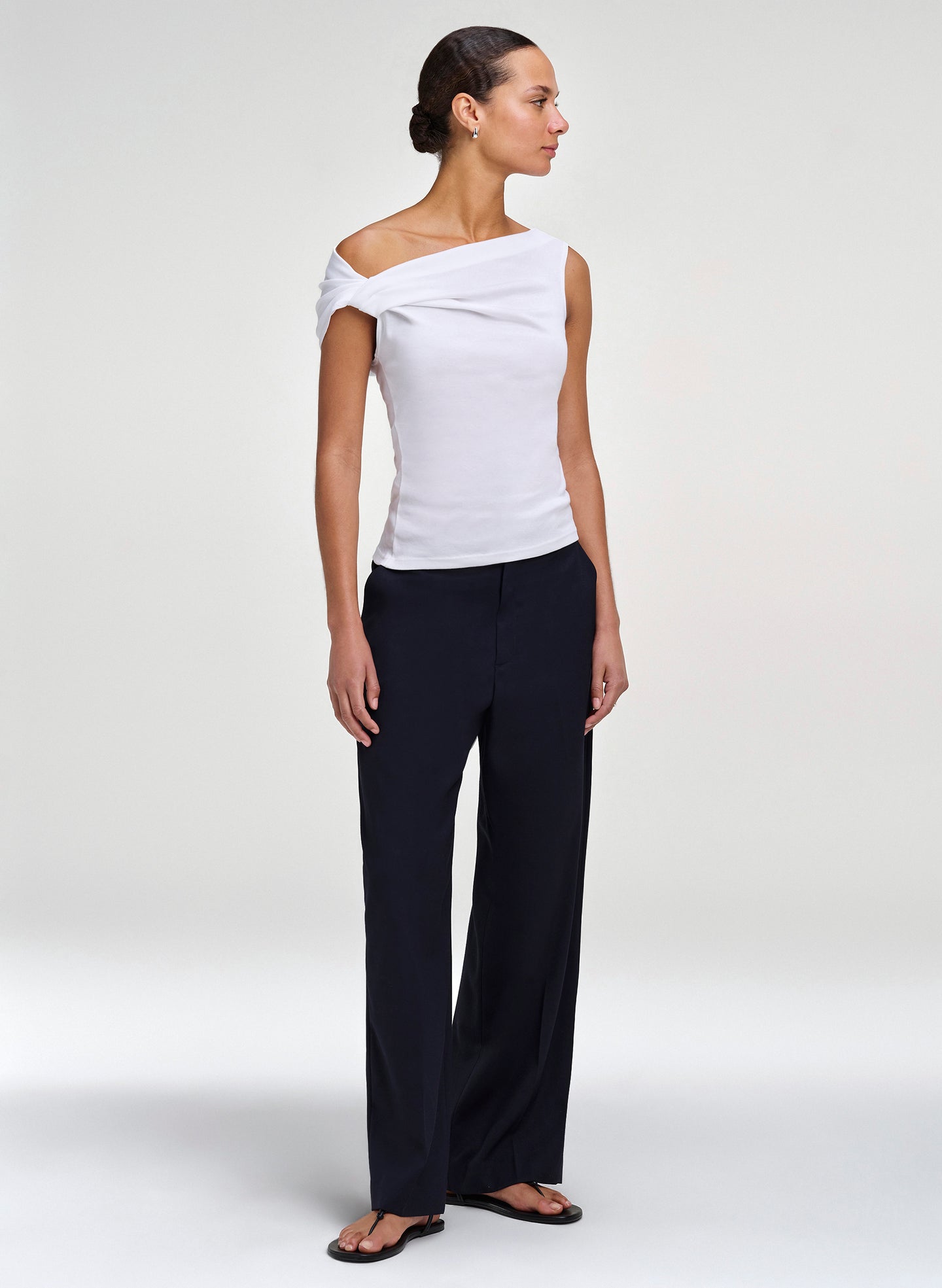Woman wearing a white off-shoulder top and black pants on a white background