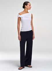 Woman wearing a white off-shoulder top and black pants on a white background