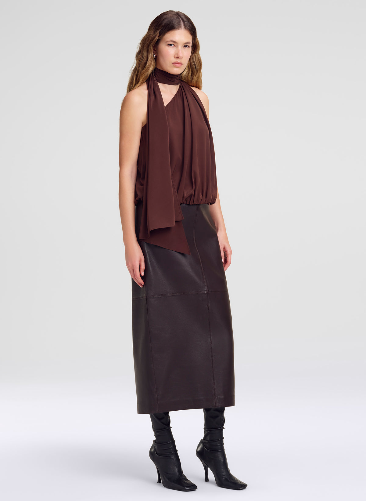 woman wearing brown silk sleeveless top and maroon leather midi skirt