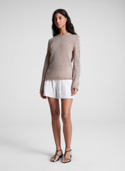 woman wearing tan sweater and white shorts